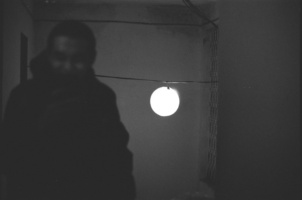 uma foto em preto e branco de uma pessoa em um quarto escuro