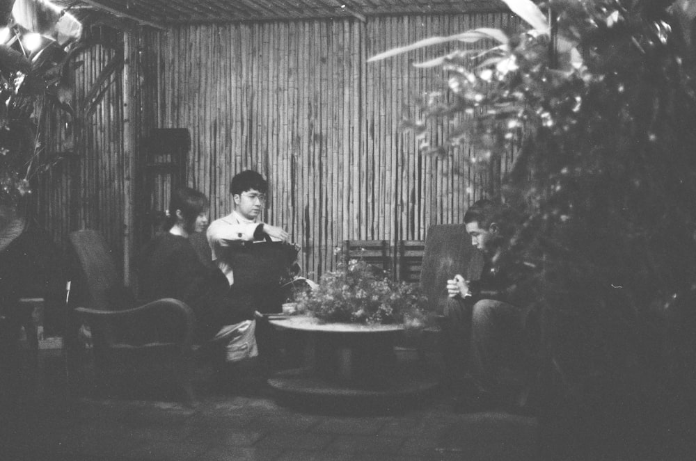 a black and white photo of people sitting around a table