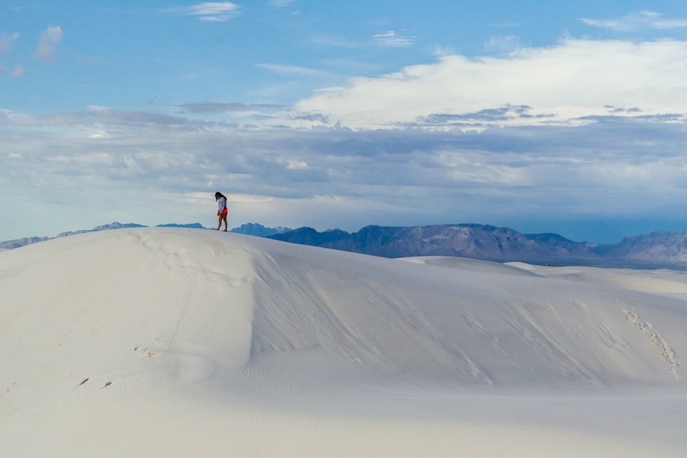 a person standing on top of a white sand dune