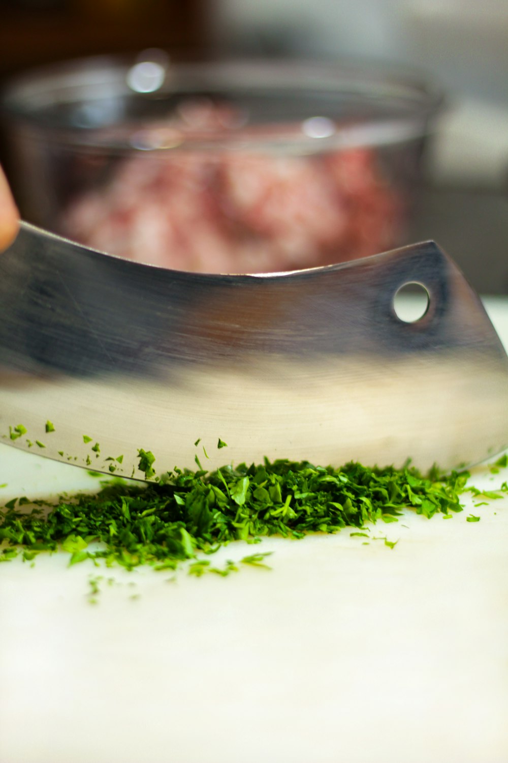 a person chopping green herbs on a cutting board