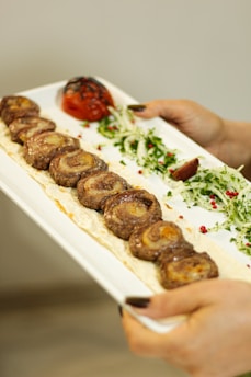 A close-up of a plate filled with traditional Armenian tolma wrapped in grape leaves, garnished with fresh herbs.