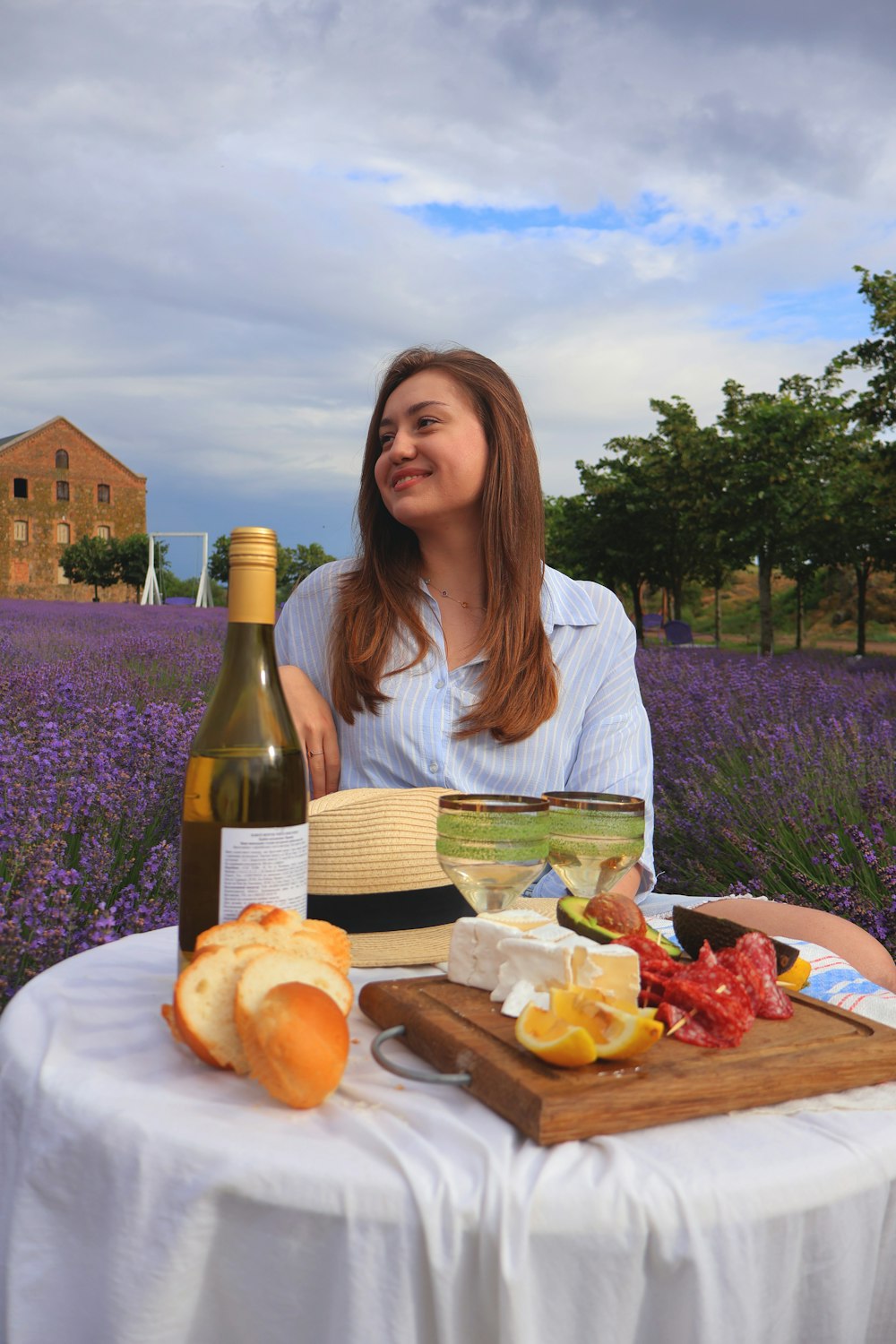 a woman sitting at a table with a bottle of wine