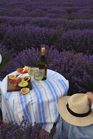 a person sitting at a table with a bottle of wine and a plate of food