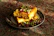 Close-up of hands delicately garnishing saffron rice with barberries and pistachios.