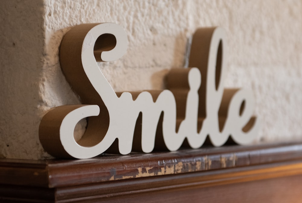 a wooden sign that says smile on a mantle