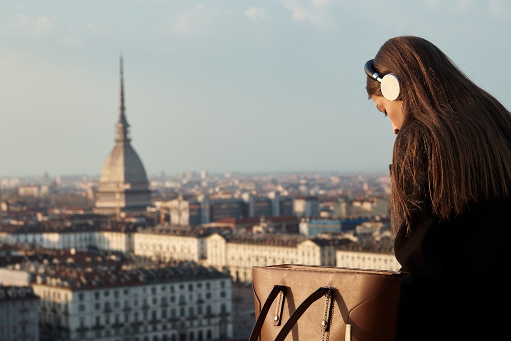 a woman sitting on top of a building looking at the city