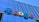 The image displays a large, colorful sign with the word 'Google' mounted on the exterior of a modern glass building. The letters are in bold, distinctly colored fonts against a backdrop of reflective windows and metallic structures.