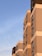 Several modern residential buildings with multiple floors and large windows are positioned under a clear blue sky. The sunlight casts warm tones on the facades, creating an interplay of light and shadows.