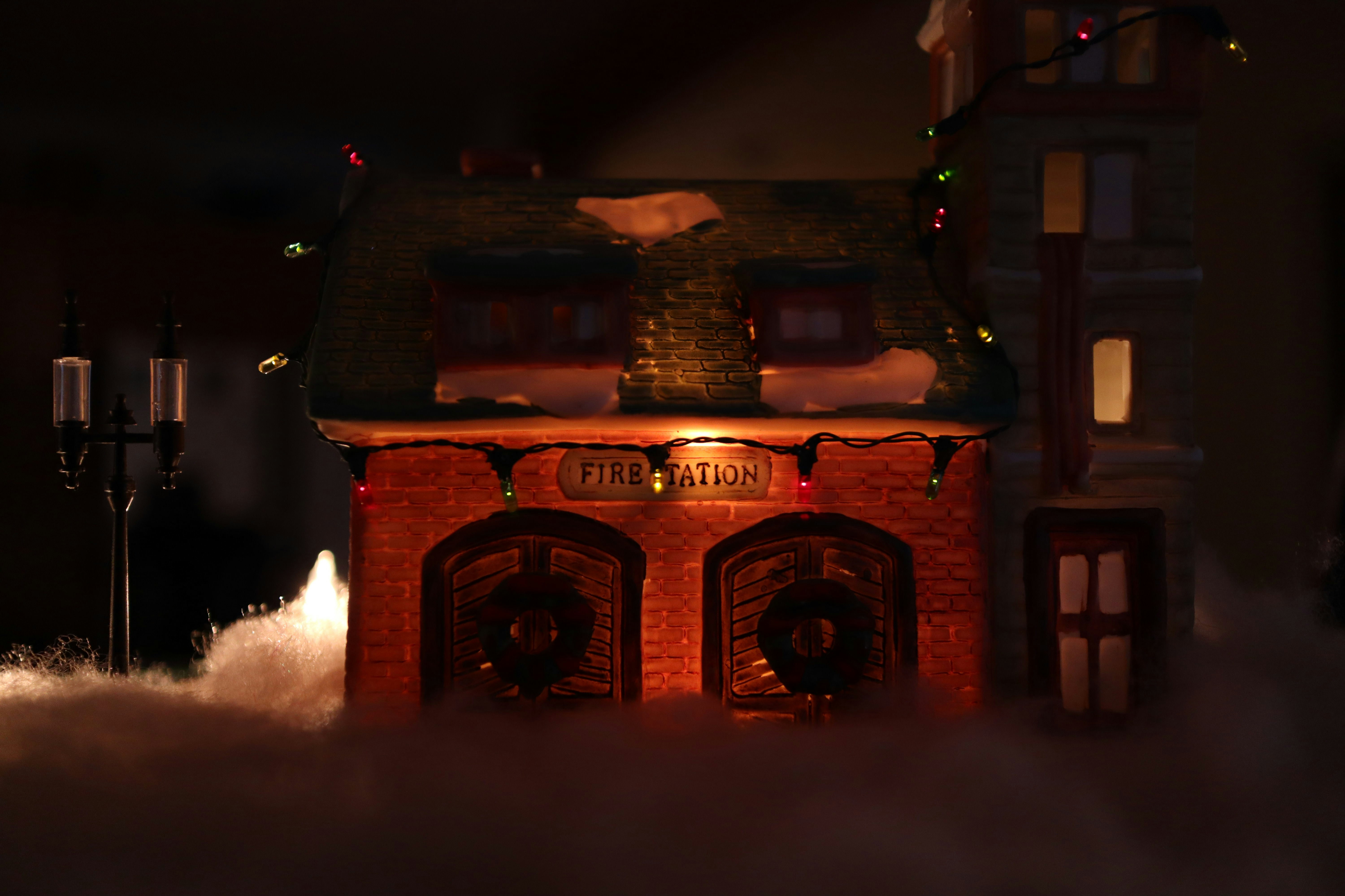 a small building with a lit up sign on top of it, Toy fire station with christmas lights