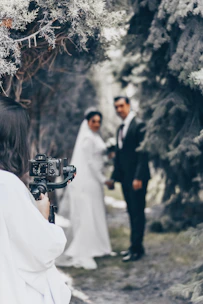 A candid shot of a photographer capturing a joyful wedding moment outdoors.