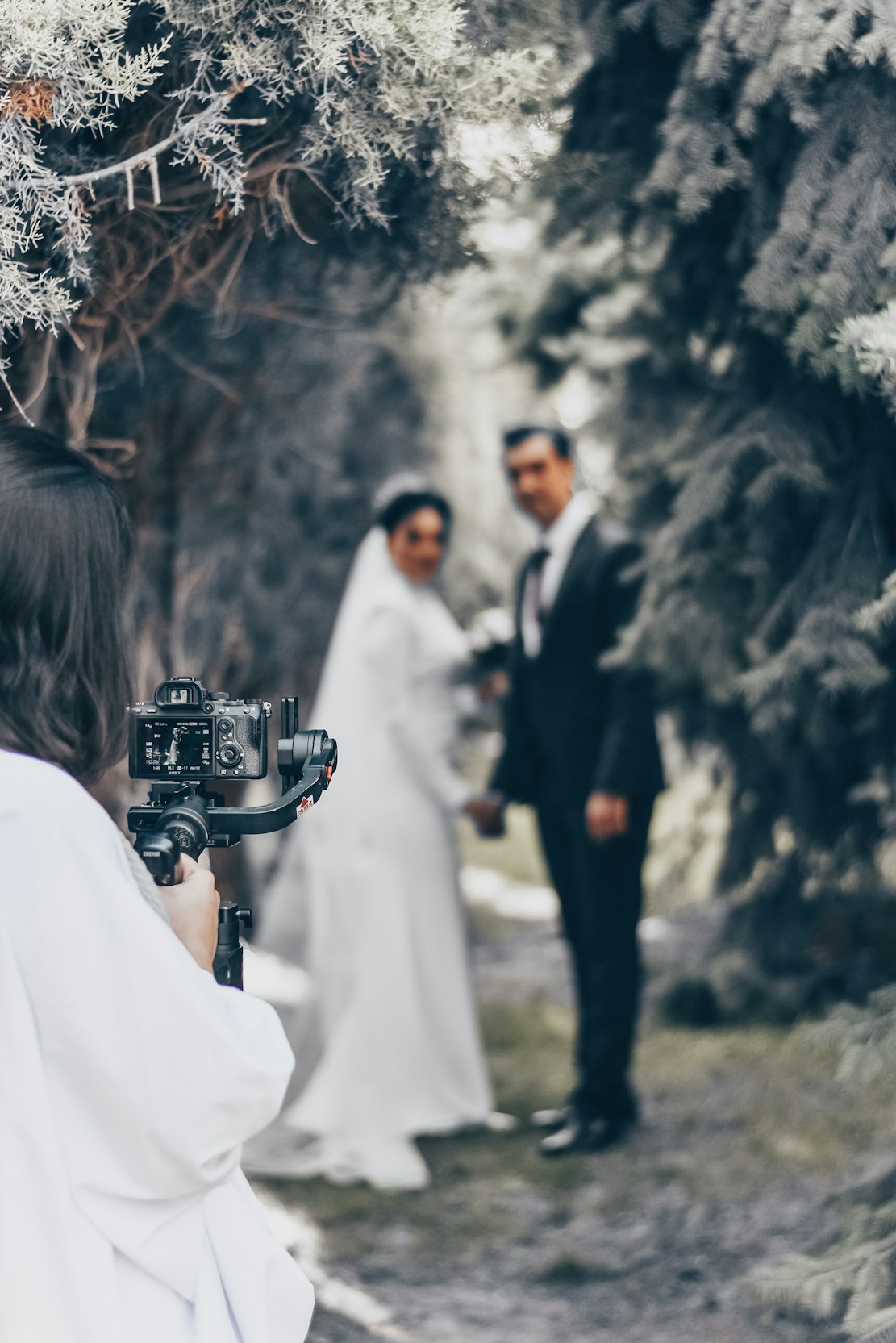 A bright, lively photo of a photographer capturing a candid wedding moment outdoors.