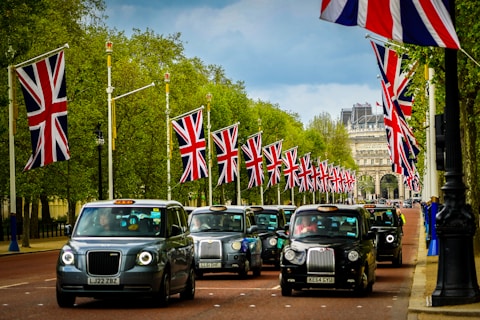 a group of cars driving down a street next to flags