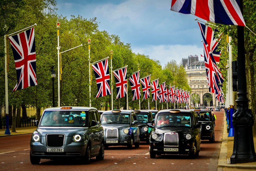 a group of cars driving down a street next to flags