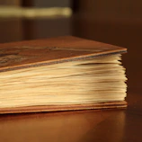 Close-up of hands holding a vintage book against a backdrop of linen fabric.