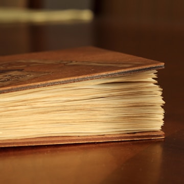 Close-up of an antique-style book with delicate embossed cover, resting on a wooden table.