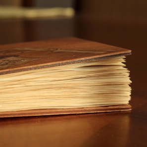 A close-up of a well-worn copy of a classic literature book resting on a rustic table.