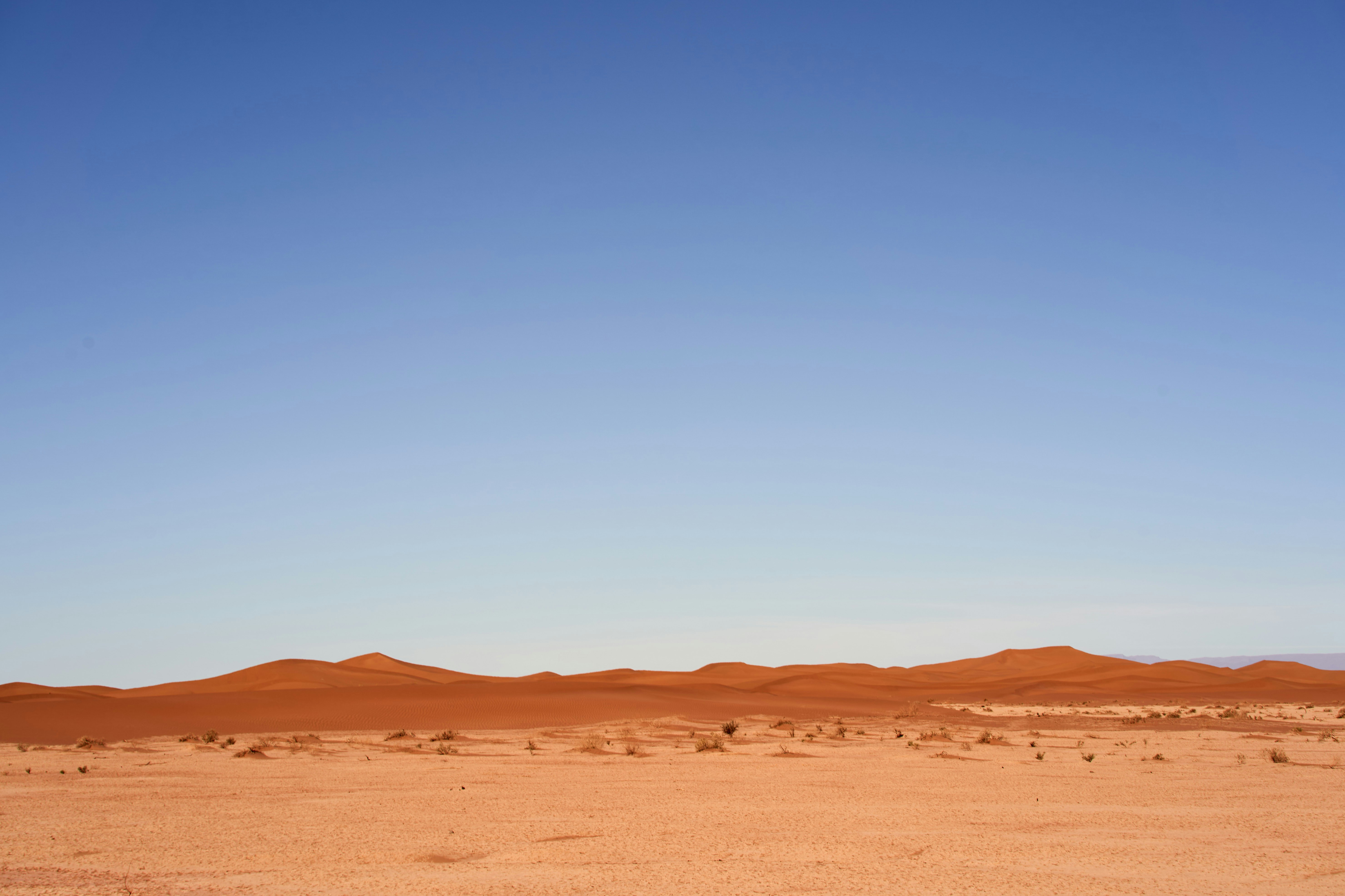 a desert with a few sand dunes and a clear blue sky