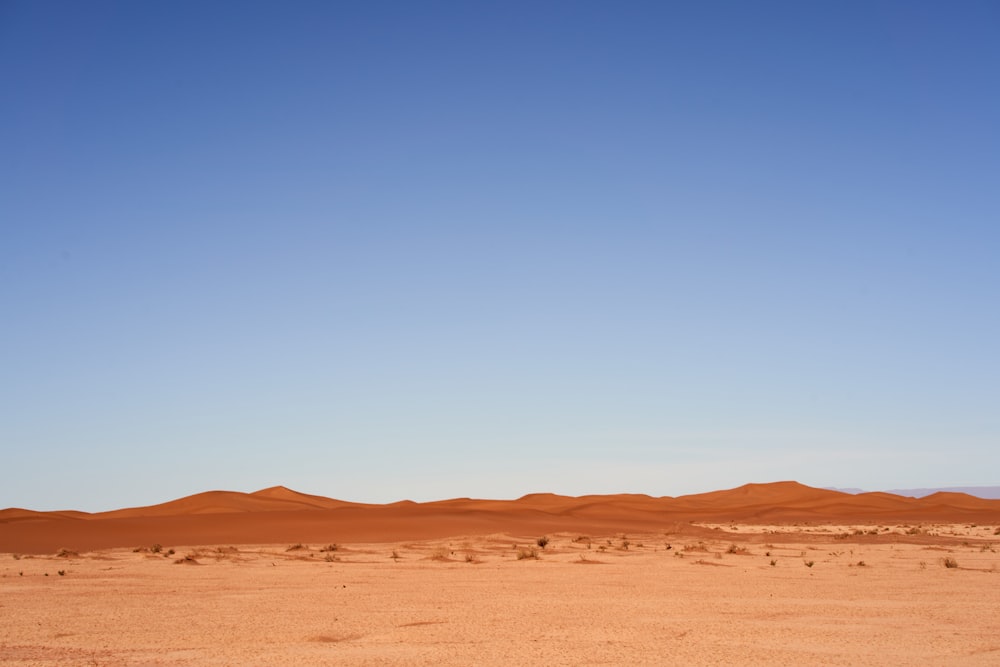 a desert with a few sand dunes and a clear blue sky