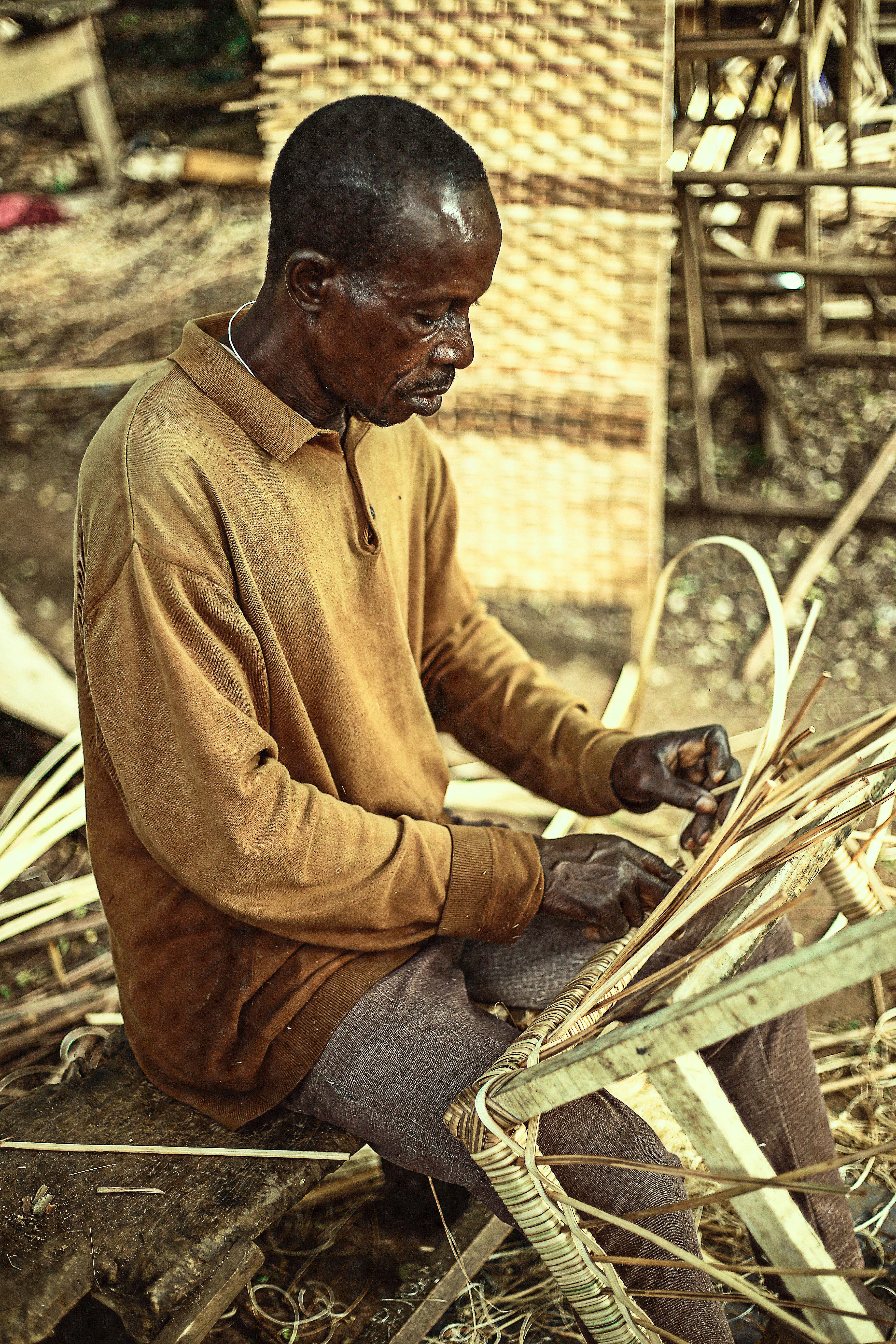 a man sitting on the ground working on a piece of wood