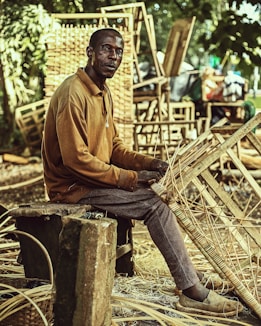 a man sitting on a wooden bench holding a bamboo basket