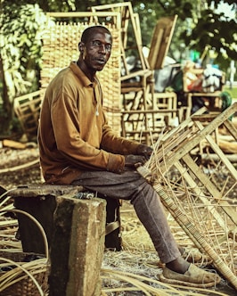 a man sitting on a wooden bench holding a bamboo basket