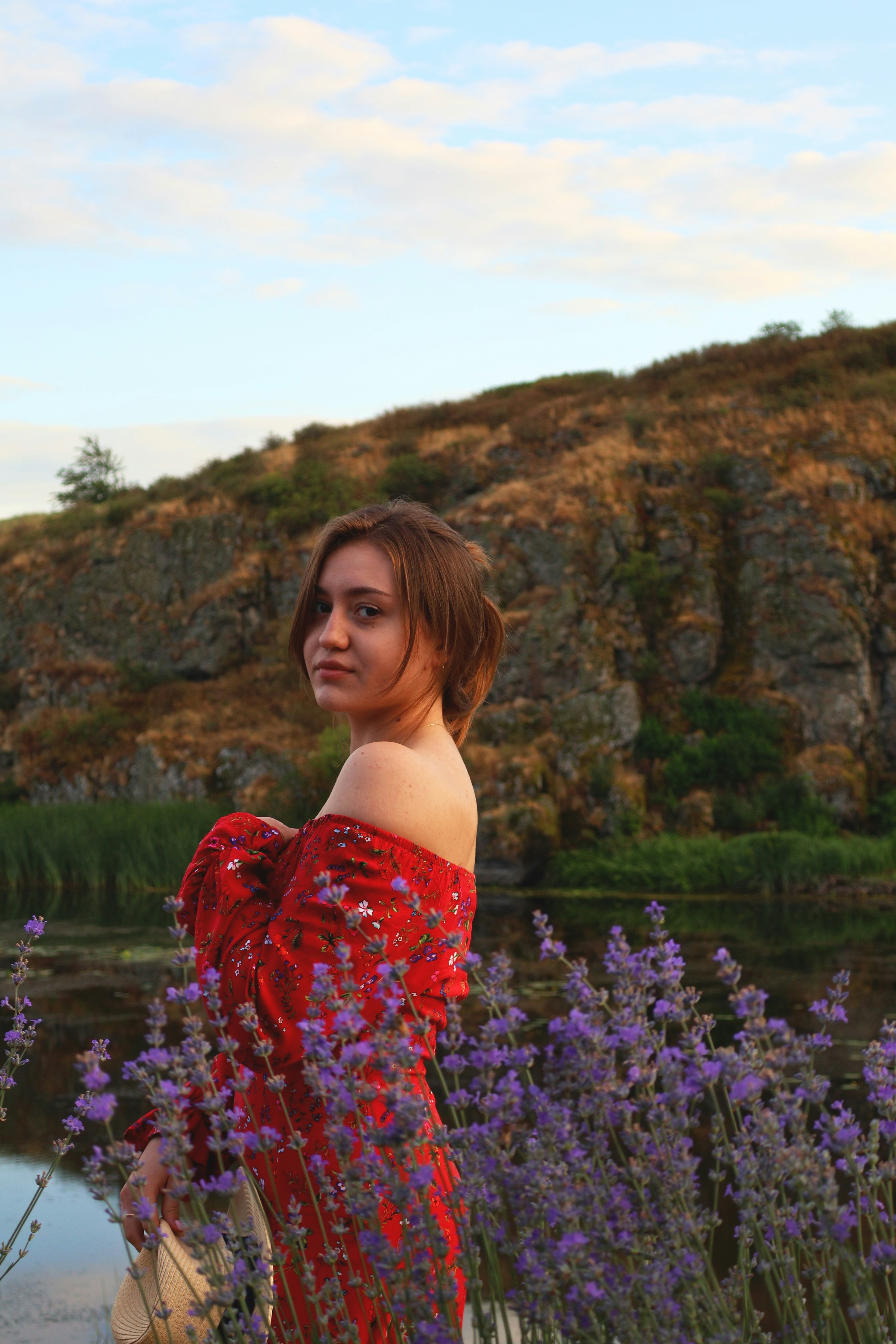A woman in a red dress standing in a field of purple flowers photo ...
