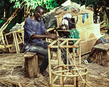 A craftsman shaping a custom teak outdoor chair in a bright workshop.