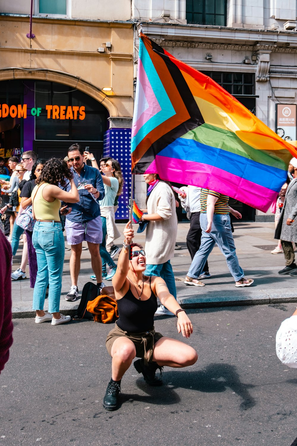 a woman kneeling down holding a rainbow colored kite