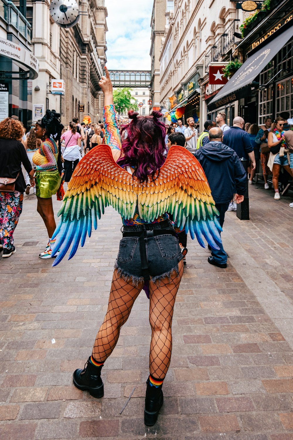 a woman in fishnet stockings and fishnet stockings is holding a colorful bird wings