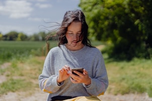 a woman sitting on a bench looking at her cell phone