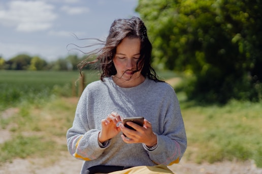 a woman sitting on a bench looking at her cell phone