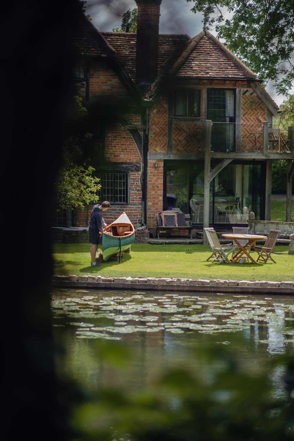 a man standing in front of a house next to a body of water