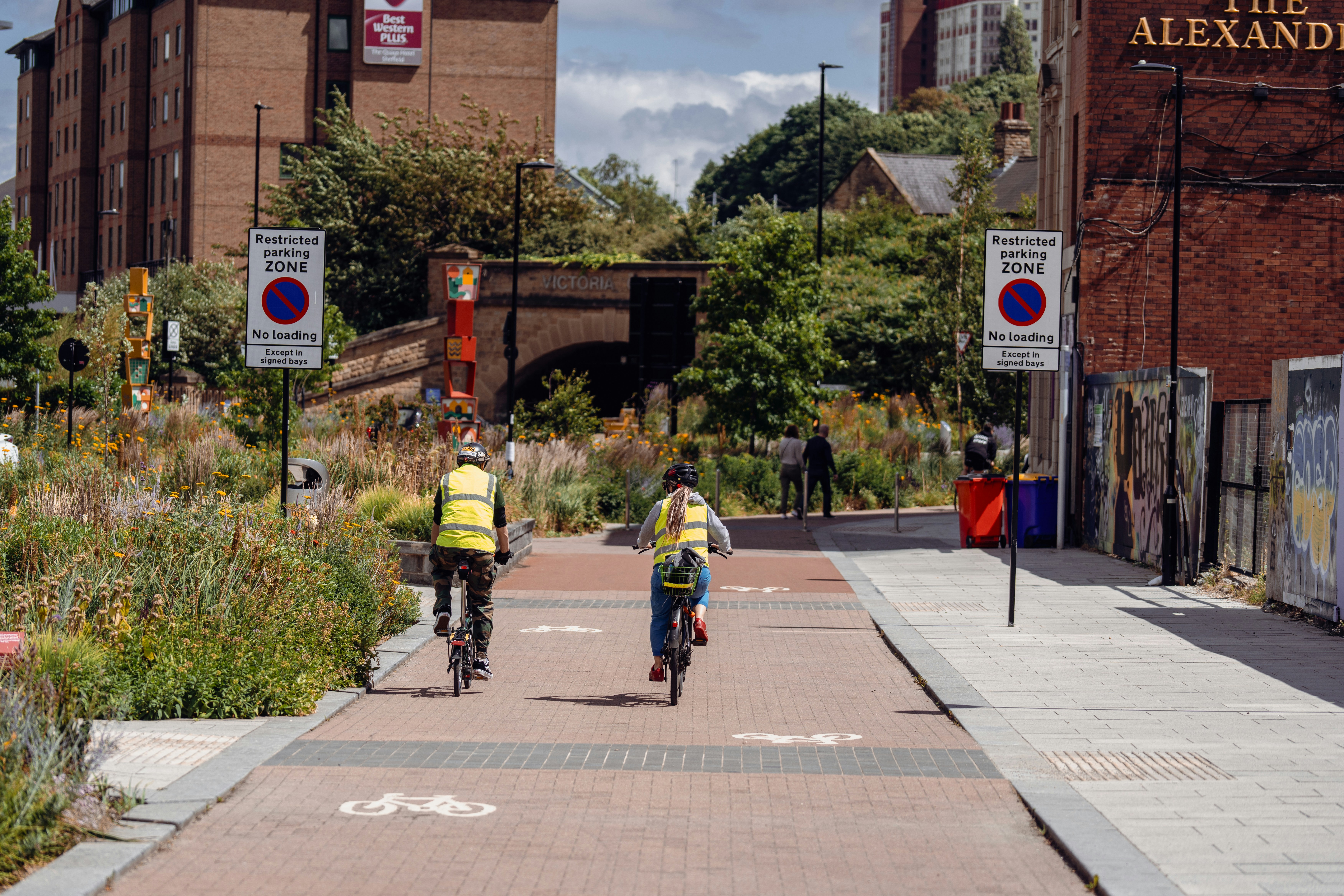 a couple of people riding bikes down a sidewalk