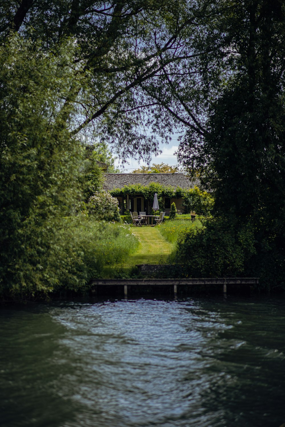 a house sitting on top of a lush green field next to a river