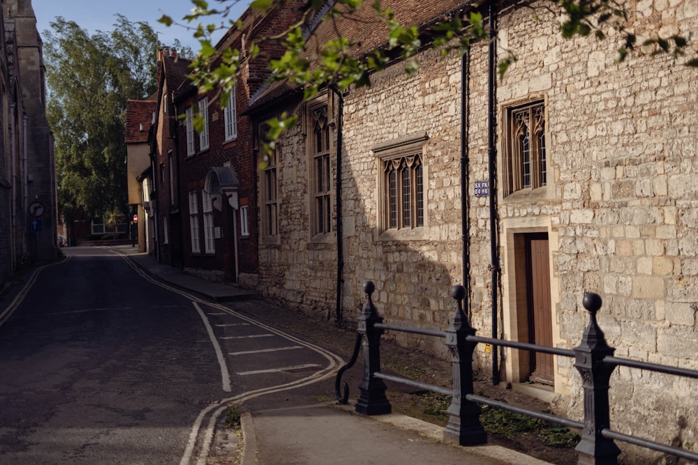 a narrow street lined with stone buildings and a metal fence