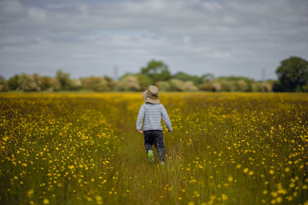 a little boy walking through a field of yellow flowers