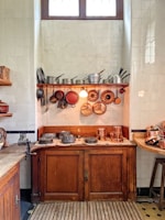 A rustic kitchen featuring clay pots on a wooden shelf.
