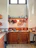 A cozy kitchen corner with hanging copper pans and rustic wooden shelves filled with colorful utensils.