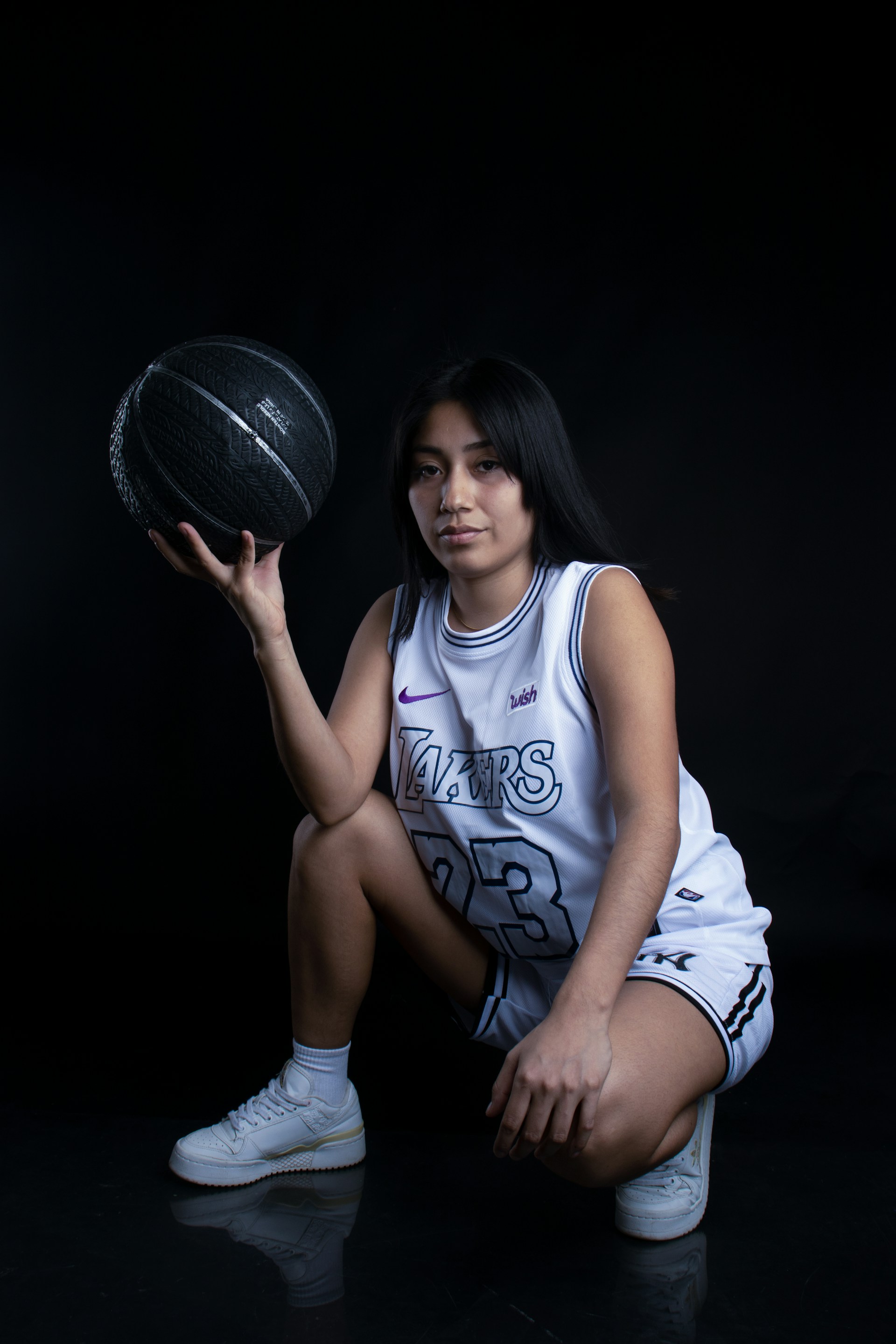 a woman sitting on the floor holding a basketball