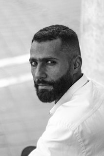 A black and white portrait of Carlos Fonseca, showing his determined gaze and signature beard.