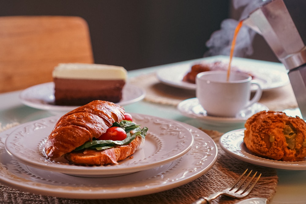 a croissant sandwich on a plate with a knife and fork