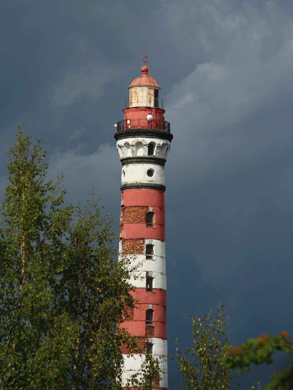 Un faro rosso e bianco con alberi in primo piano