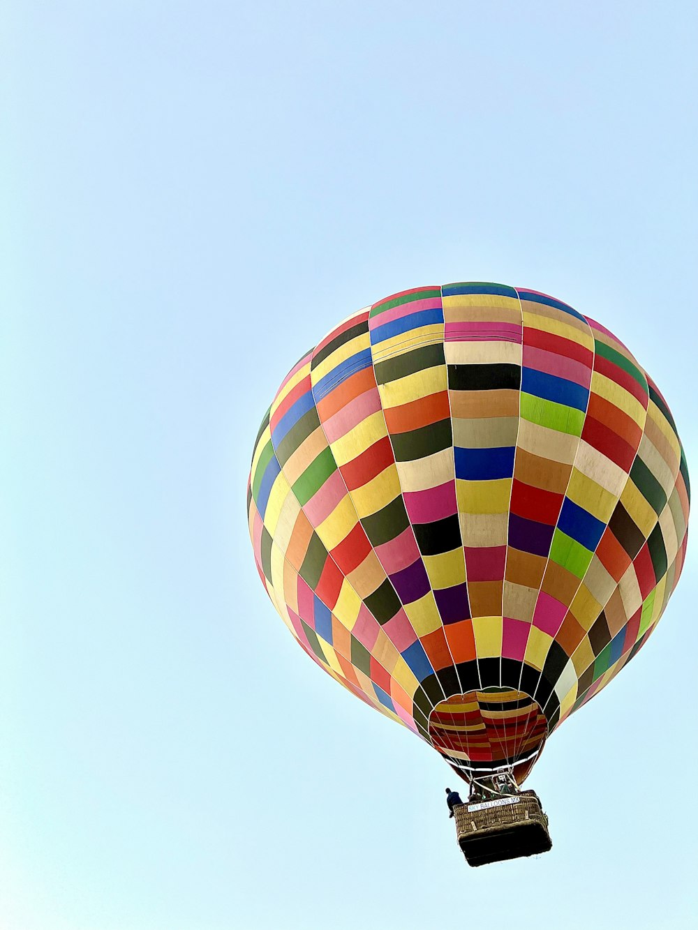 a multicolored hot air balloon flying in a blue sky