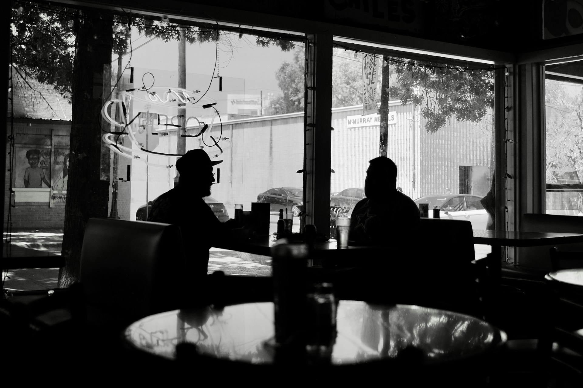 two people sitting at a table in front of a window