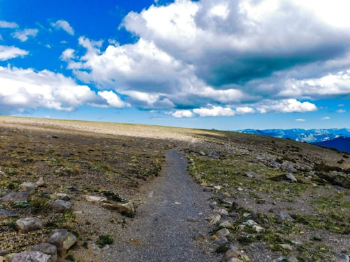 A rugged mountain trail winding under a bright blue sky, inviting adventure.