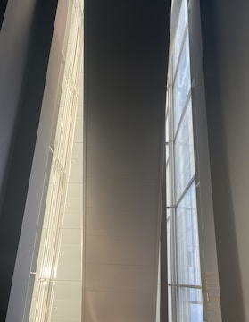 A modern home featuring a large glass curtain wall that floods the interior with natural light.