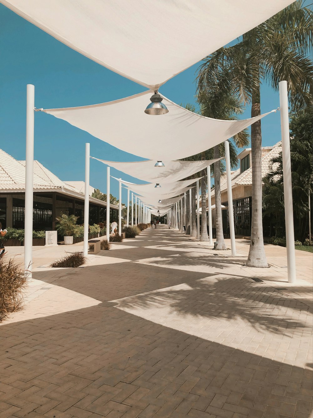 a walkway lined with white poles and white awnings