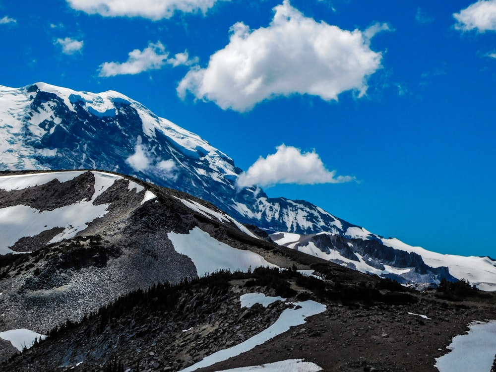 a snow covered mountain under a blue sky with clouds