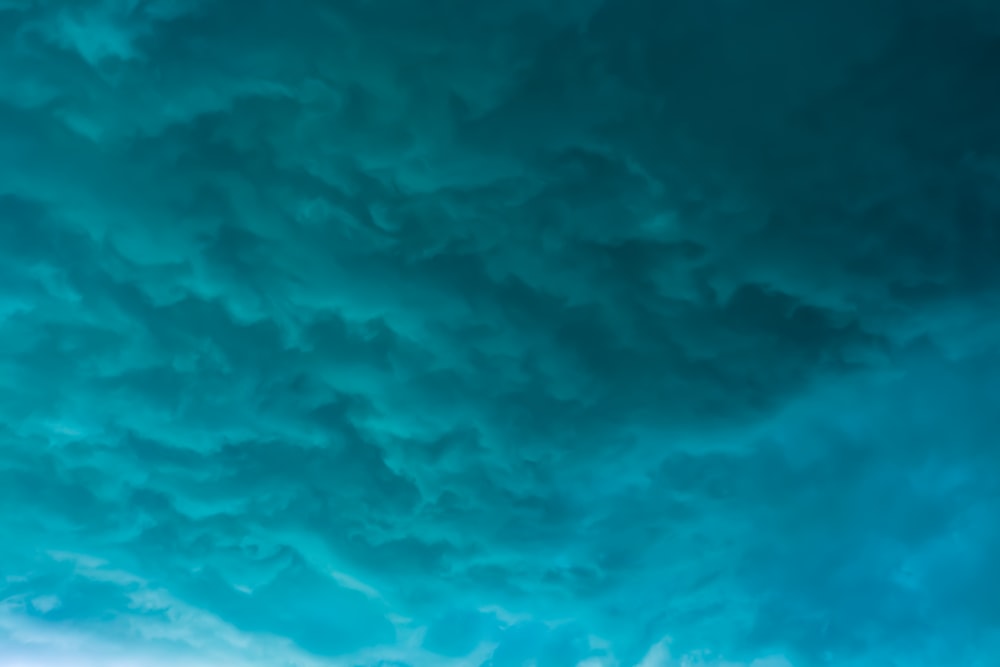 a plane flying through a cloudy blue sky