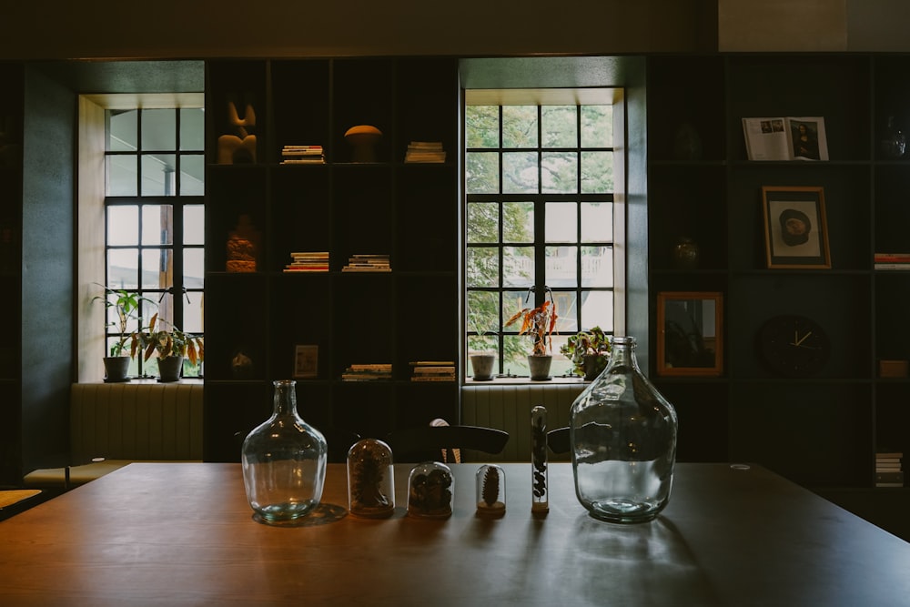 a wooden table topped with two glass vases